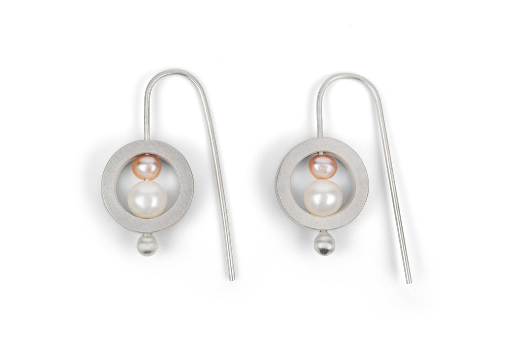 Pair of silver earrings with a central pearl on a white background
